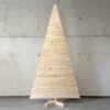 Großer Holzweihnachtsbaum in traditioneller Dreiecksform vor einer Betonwand, handgefertigt aus nachhaltigem Kiefernholz.