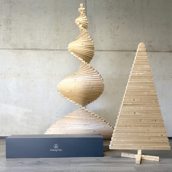 Der Xtra Franky Holzweihnachtsbaum in Spiralform und Medium Franky Holzbaum in gerader Form, mit dem Versandkarton aus recyceltem Plastik.