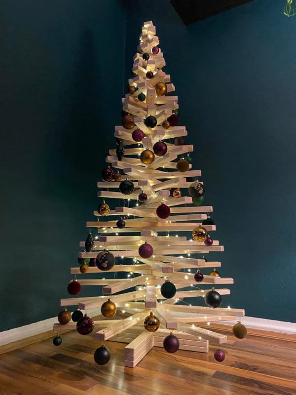 Geschmückter Holzweihnachtsbaum aus Fichtenholz mit Lichterkette und braunen Kugeln