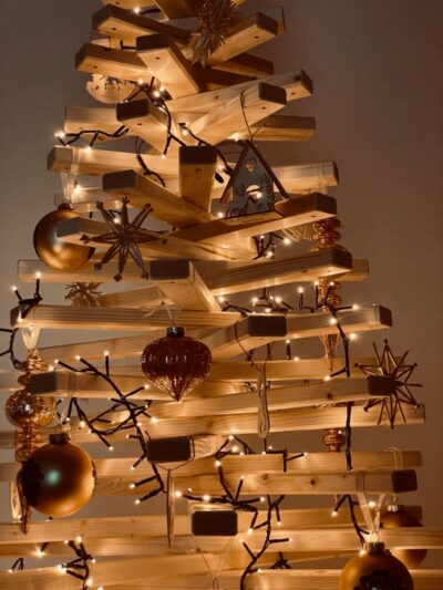 Aussschitt von einem Weihnachtsbaum aus Holz mit einer Lichterkette und Holzelementen geschmückt