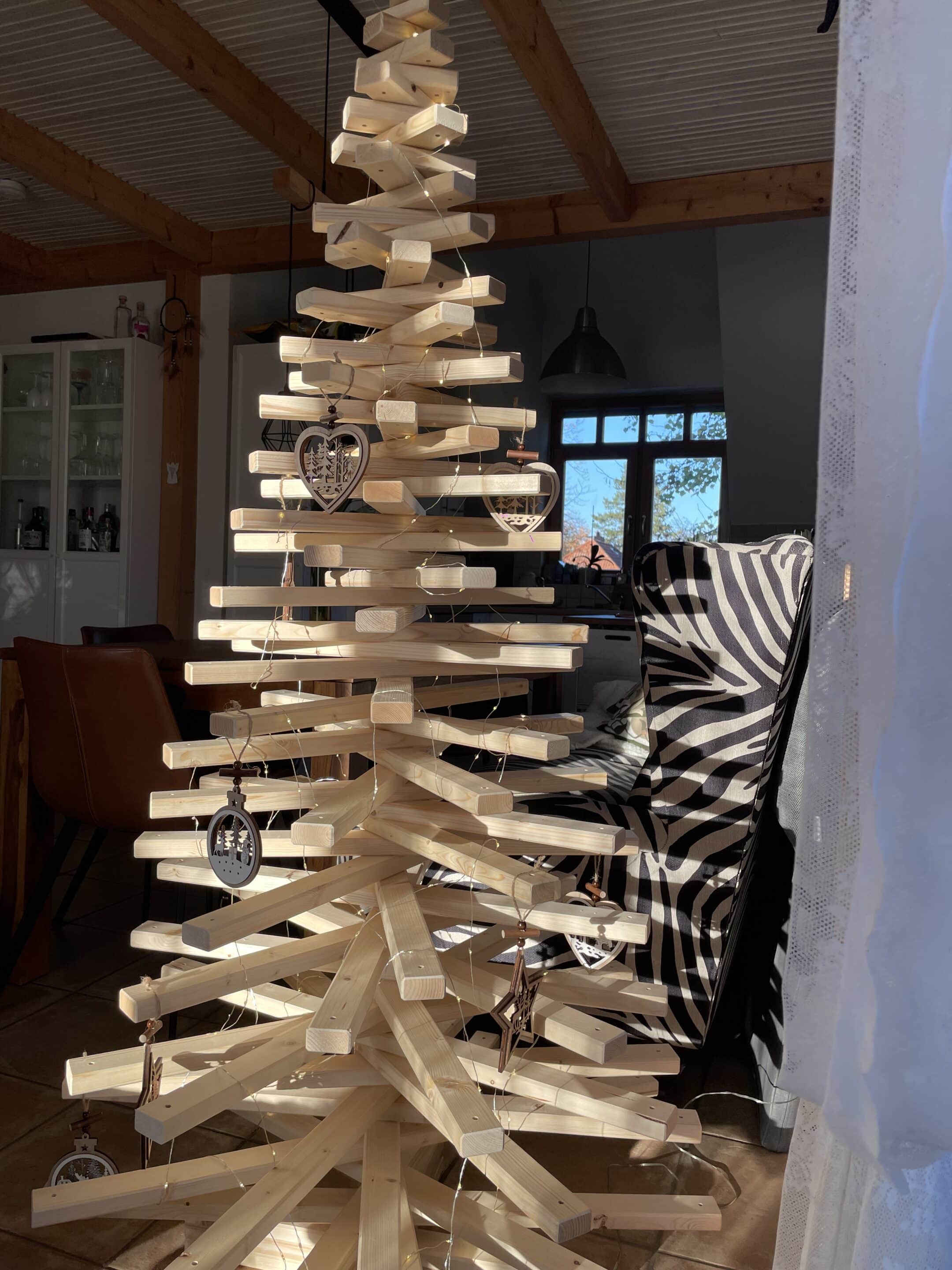Dekorierter Christbaum aus Fichtenholz vor einem Fenster, beleuchtet mit einer Lichterkette