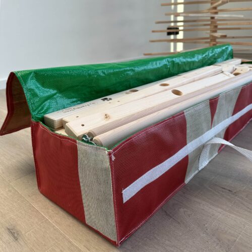 Upcycling-Tasche von Fyksin für die Aufbewahrung eines Franky Tree Holzweihnachtsbaumes, hergestellt aus alten Werbebannern, mit den zerlegten Baumteilen darin.