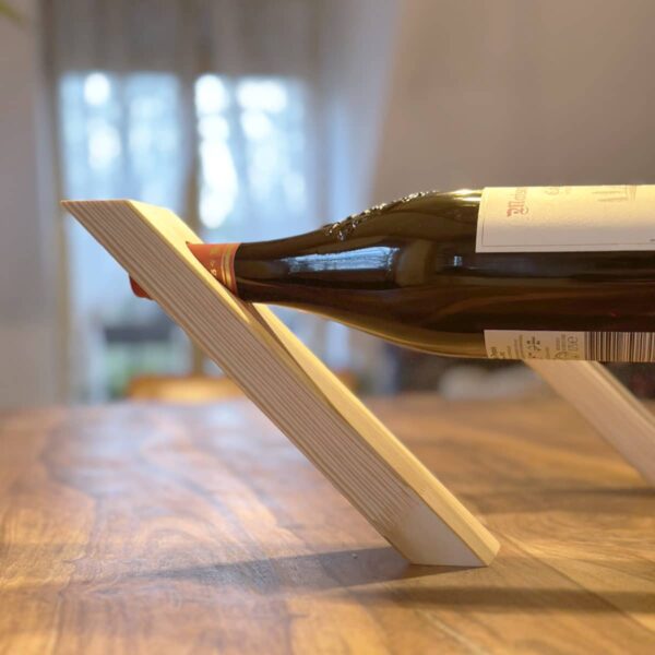 Handgefertigtes schwebendes Weinregal aus Kiefernholz, präsentiert mit einer Weinflasche, aufgestellt auf einem Holztisch.