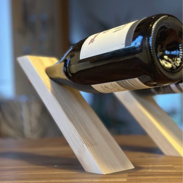 Detailaufnahme eines handgefertigten schwebenden Weinregals aus Kiefernholz, das eine Weinflasche elegant präsentiert.