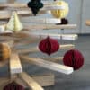 Nahaufnahme eines Large Franky Holzweihnachtsbaumes, geschmückt mit Papieranhängern in Wabenstruktur in warmen Farben wie Rot, Weiß und Gold.