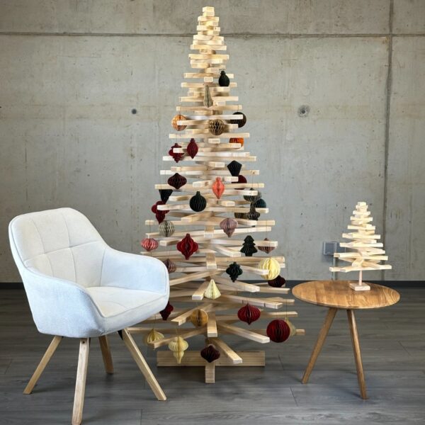 Holzweihnachtsbaum Large Franky Tree, geschmückt mit Papieranhängern in Wabenstruktur, steht neben einem Stuhl und einem Tisch, um die Größe des Weihnachtsbaumes im Verhältnis zu verdeutlichen.