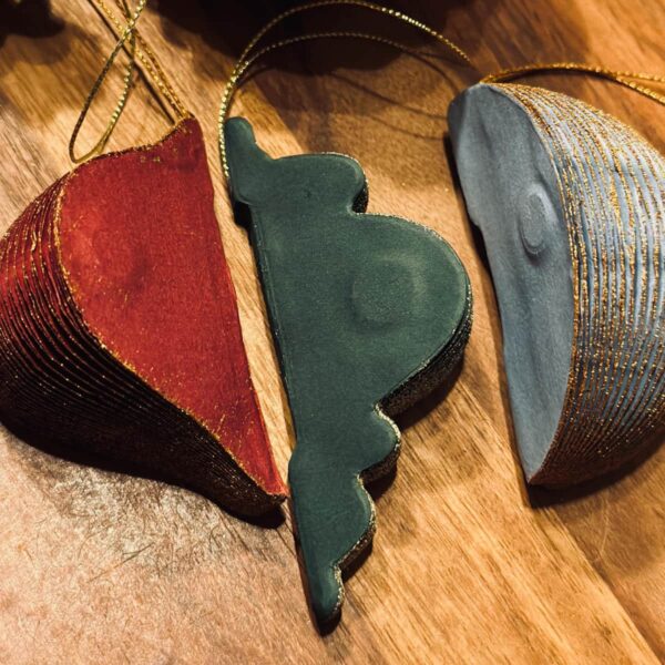 Nahaufnahme von nachhaltigen Papieranhängern in Wabenstruktur, magnetisch verschließbar, in festlichen Farben wie Rot und Grün.