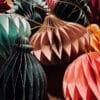 Nahaufnahme von nachhaltigen Papieranhängern in Wabenstruktur in Farben wie Grün, Beige, Rosa und Rot mit goldenen Akzenten.