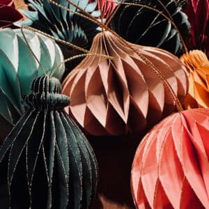 Nahaufnahme von nachhaltigen Papieranhängern in Wabenstruktur in Farben wie Grün, Beige, Rosa und Rot mit goldenen Akzenten.