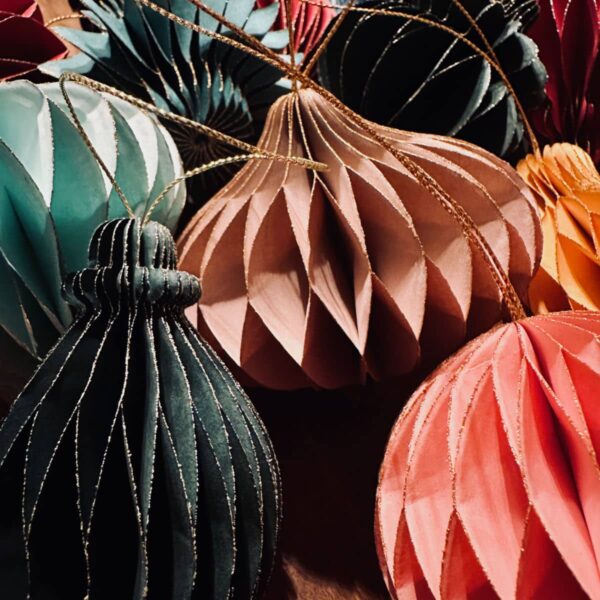 Nahaufnahme von nachhaltigen Papieranhängern in Wabenstruktur in Farben wie Grün, Beige, Rosa und Rot mit goldenen Akzenten.